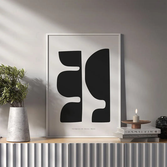Plakat z czarno-białą, abstrakcyjną grafiką przedstawiającą kompozycję geometrycznych kształtów i form wiszący w salonie