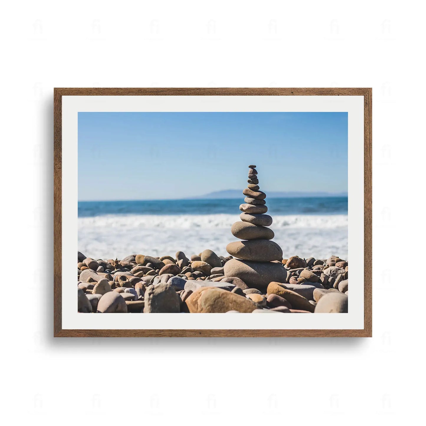 Stos okrągłych kamieni ułożonych w idealnej równowadze na kamienistej plaży, na tle spienionych fal i oceanu.