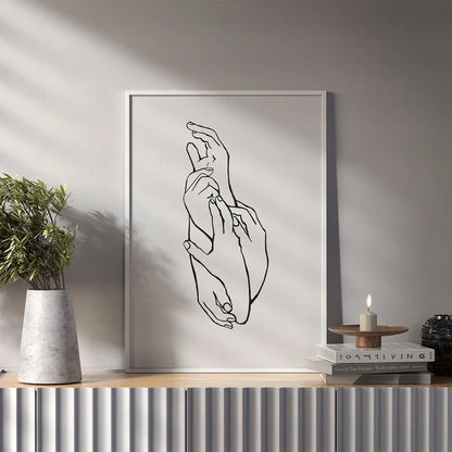 Plakat z czarno-białą grafiką line art przedstawiającą dwie dłonie w geście delikatnego dotyku. w salonie
