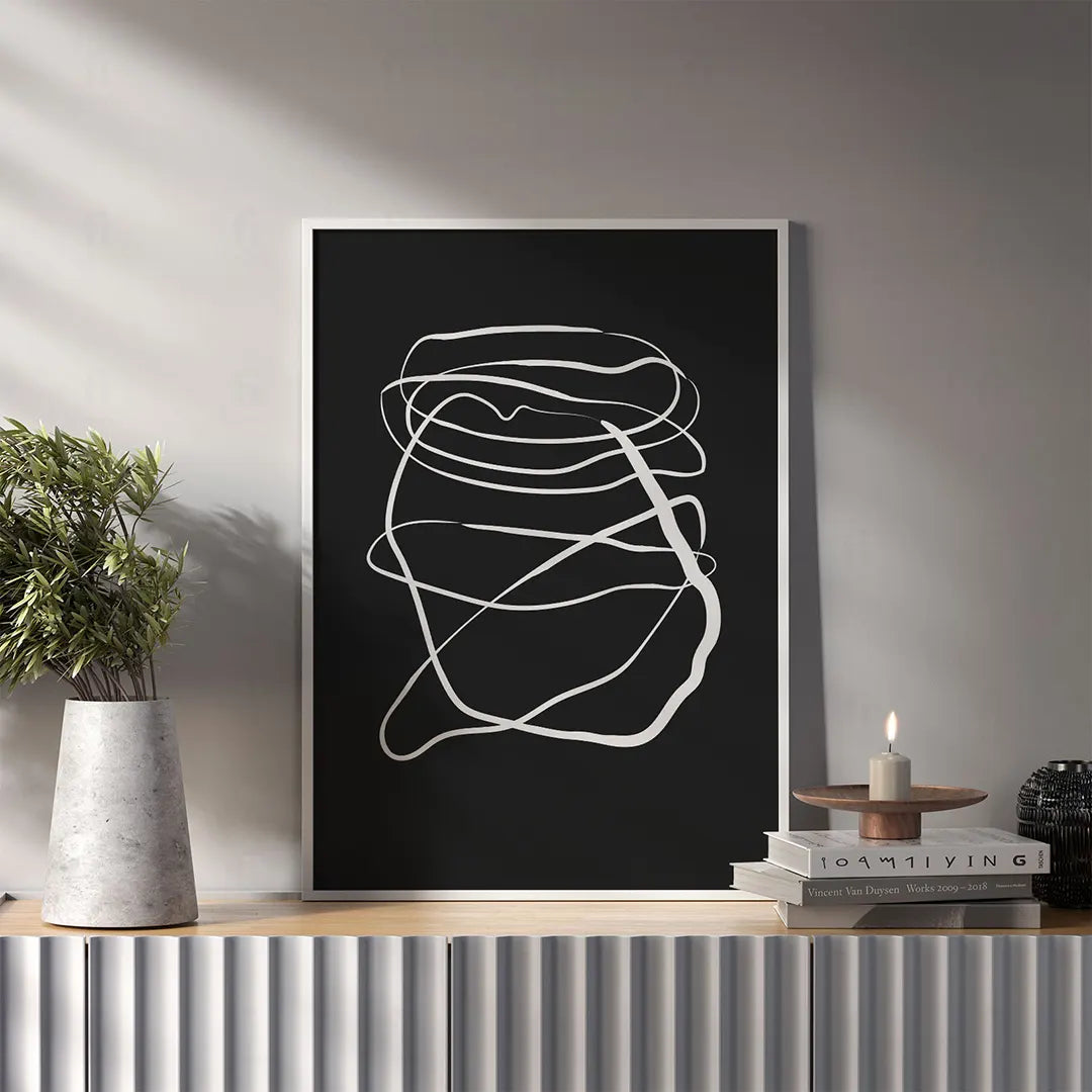Plakat z czarno-białą, abstrakcyjną grafiką w stylu swobodnego szkicu wykonanego jedną linią wiszący w salonie