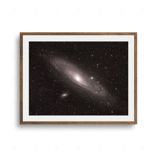 Zdjęcie astronomiczne przedstawiające Galaktykę Andromedy na tle ciemnego kosmosu pełnego gwiazd.